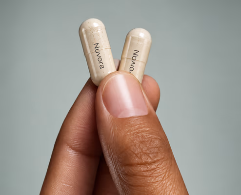 Two Nuvora capsules held between finger and thumb
